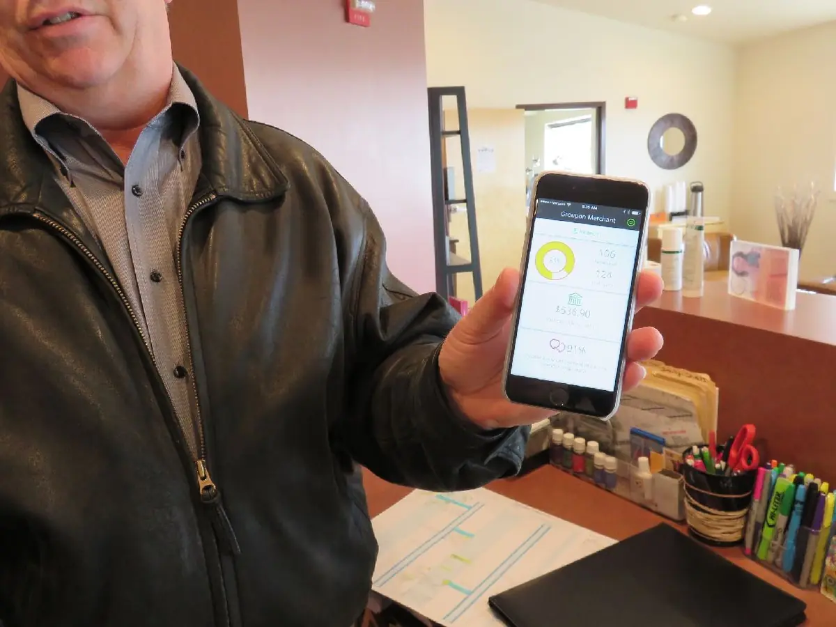 A spa manager shows the Groupon merchant app on a phone during a field visit