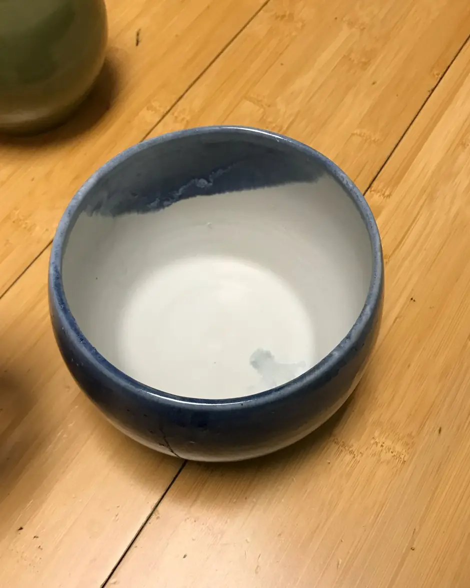 A bowl with a white glaze and a cobalt blue rim on a wooden table
